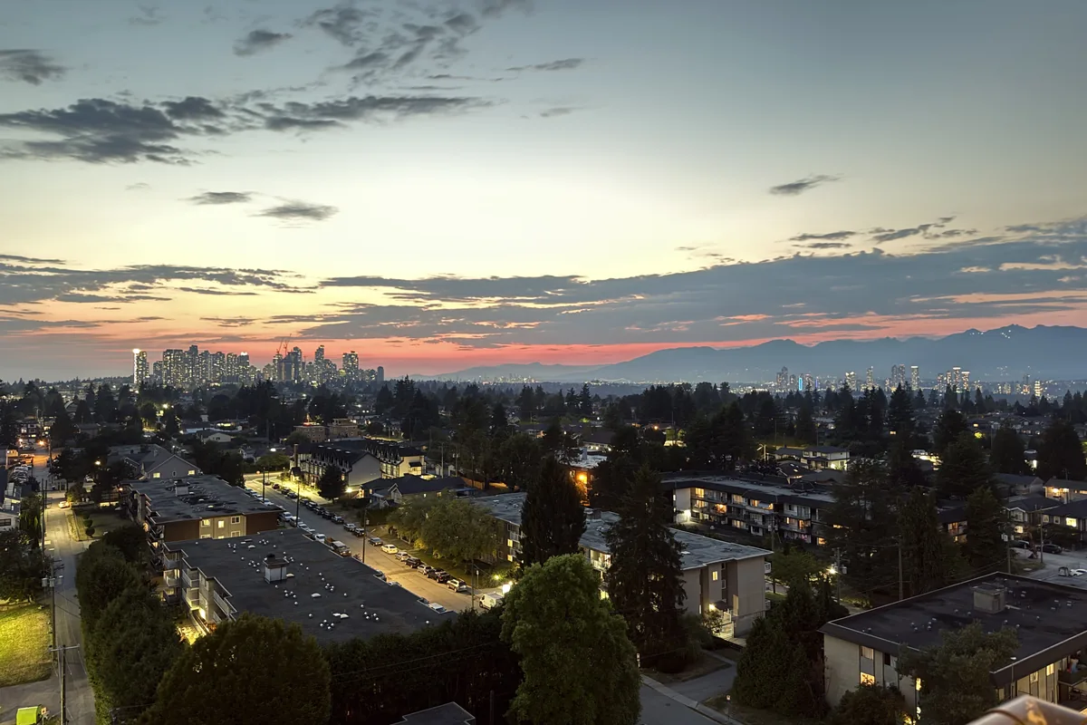 Twilight view of Metro Vancouver neighbourhoods and high-rises under an orange sunset