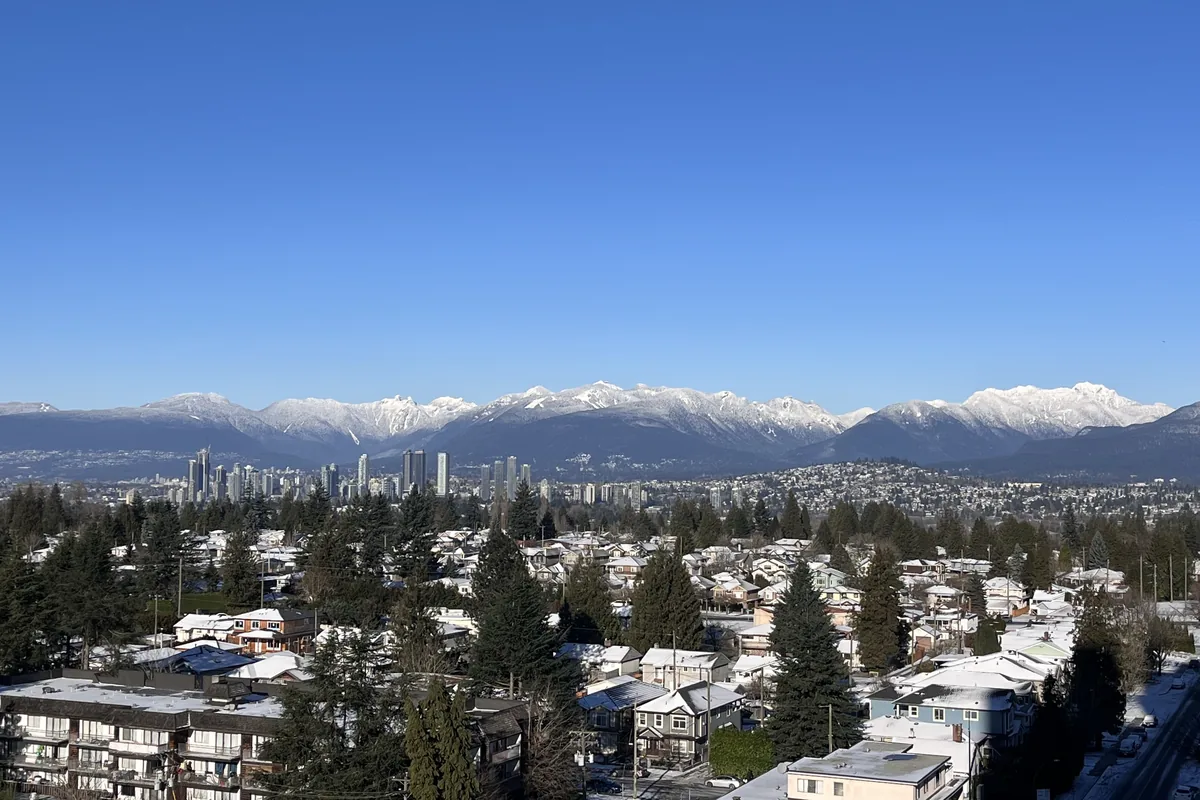 Winter view across Metro Vancouver homes and skyline toward the snow-capped North Shore mountains